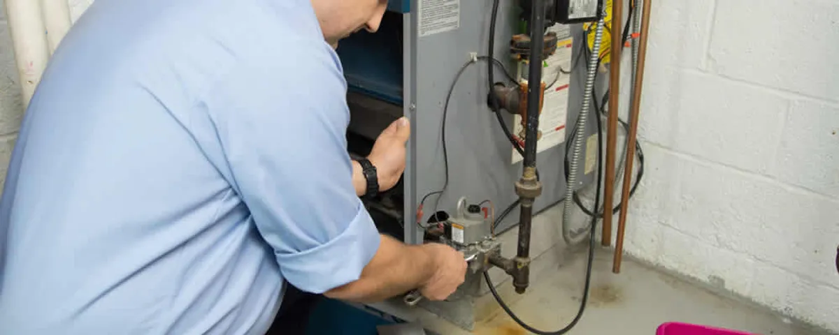 Furnace repair technician inspecting and servicing a home heating system in Fresno, CA